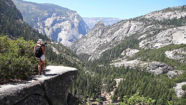 Travel photographer on John Muir trail from the Nevada Falls on Merced River in Yosemite National Park. Woman mountain hiker in Yosemite, California, United States.