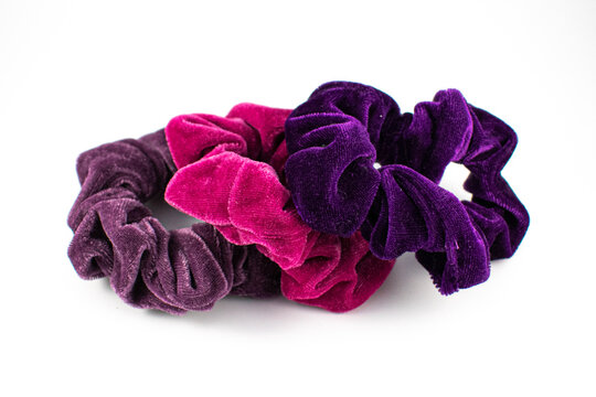 Photo of three velvet scrunchies in pink and purple shades. 