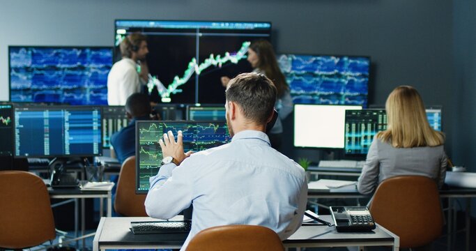 Portrait of multi-ethnic team of traders and brokers working at stock exchange office. Monitors Display Relevant Infographics, Data and Numbers. Global Financial Concept