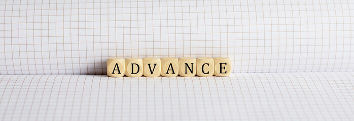 Concept ADVANCE Words written on a wooden block on notebook. Leadership concept.