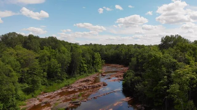 Shallow river with red rocks in the woods. Bonanza falls in Upper Peninsula. Big Iron River in the summer.