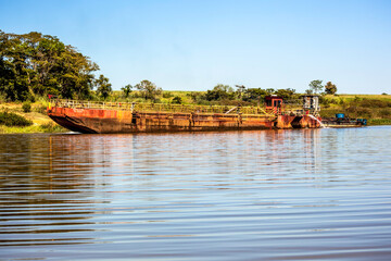 Guaraci, Sao Paulo, Brazil, April 08,2015. Boat extracts sand on the edge of an arm of Rio Grande...