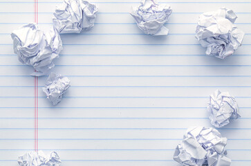School supplies of blank lined notebook paper surrounded by more trashed balled up paper. Studying...