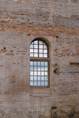 Fototapeta na wymiar Vintage window overlooking the clouds. Wooden frame with small cells. Old red brick wall. Weathering, cracks. Concept of a medieval castle, antiquity.