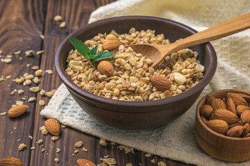 Granola with almonds in a clay Cup on a wooden table.