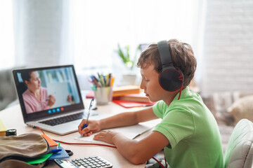 small boy uses laptop to make video call with his teacher. over his shoulder