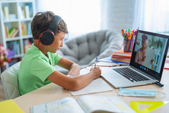 small boy uses laptop to make video call with his teacher. over his shoulder
