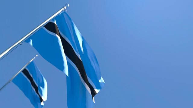 The national flag of Botswana is flying in the wind against a blue sky