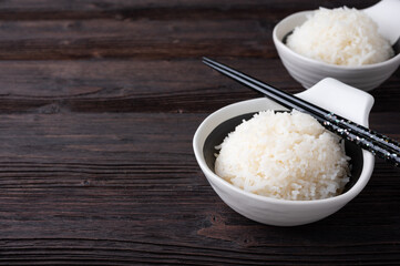 Bowl of boiled rice served on wooden table,