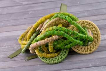 Handmade multi colour bead necklace - ranging green to cream with green ribbon on grey wood