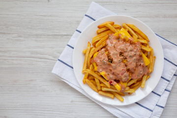 Homemade Animal Style French Fries on a white plate on a white wooden table, overhead view. Flat lay, top view, from above. Space for text.