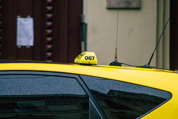 View of a traditional yellow Hungarian taxi for passengers driving under the rain through the...