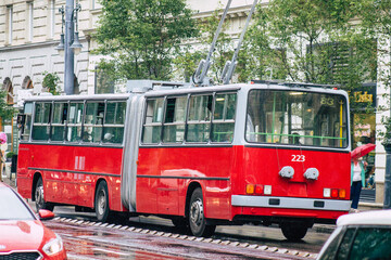 View of a traditional Hungarian red trolleybus for passengers driving under the rain through the streets of Budapest, the capital of Hungary
