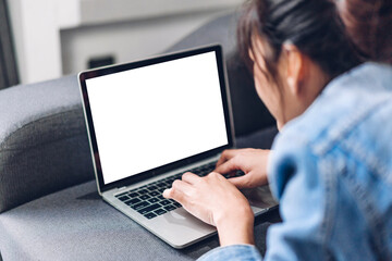 Young creative woman relaxing using laptop computer working and typing on keyboard with white mockup blank screens at home