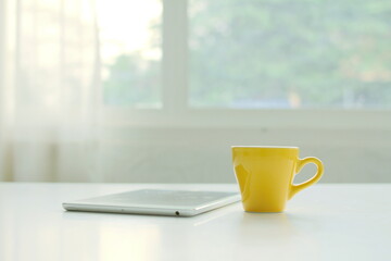 Workplace with white laptop, notebook and coffee on wooden desk .Coffee cups ,work desk has a laptop and a coffee cup.	