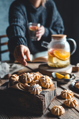 A woman reaches for a cake and drinks grapefruit tea. Healthy drink.