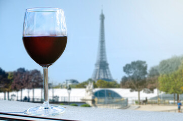 Glass of wine on Eiffel tower blur background. Sunny view of glass of red wine overlooking the Eiffel Tower in Paris, France