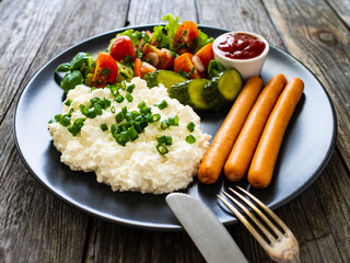 Breakfast - cottage cheese, boiled sausages and vegetables served on wooden table
