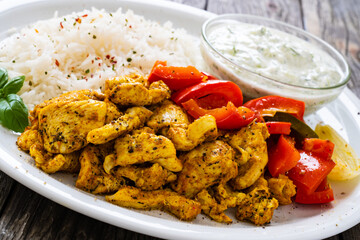 Chicken meat with rice and vegetables on wooden table
