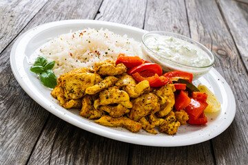 Chicken meat with rice and vegetables on wooden table
