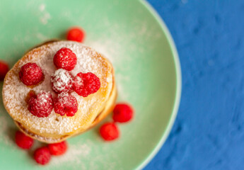 Pancakes with raspberries.A stack of fresh homemade pancakes with berries on a plate.The view from the top