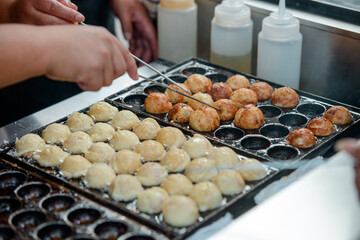 Cooking portion of Takoyaki balls in pan