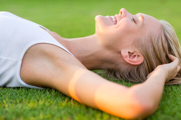 Happiness and relaxation. Happy pretty young woman lying on the grass feeling blissful and enjoying her summer day.