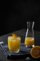 Orange juice glass with ice on dark background. Refreshment cold drink .