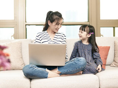 young asian woman working from home while taking care of daughter