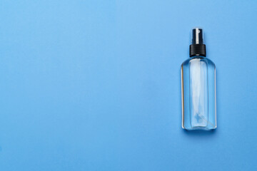 Naklejka premium Bottle of antiseptic alcohol hand sanitize spray on a blue background for the prevention of coronavirus - flat layout with copy space