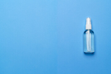 Bottle of antiseptic alcohol hand sanitize spray on a blue background for the prevention of coronavirus - flat layout with copy space