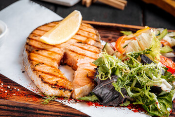 Grilled salmon steak with greens salad and lemon