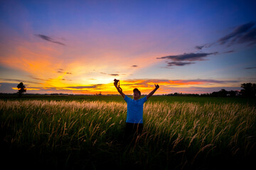 Fototapeta na wymiar A man show camera in a field of flowers grass and evening light.