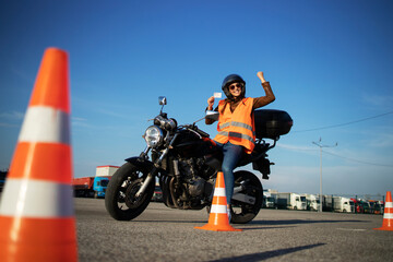 Motorcycle driving school. Student showing motorcycle driving license as successfully finished riding lessons.