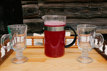 Berry compote on the table. Raspberry, currant or strawberry mors in a glass jug on a rustic background and two glasses. © d_odin