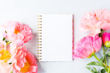 Workplace, desktop view. pink peony and blank notebook. Woman workspace. Copy space. Mock up.