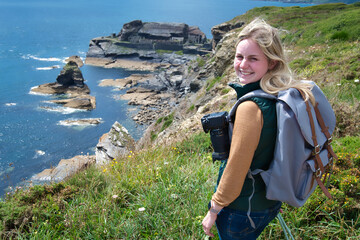 Blond woman with camera exploring the coast of France brittany at Îlot des Capucins near Roscanvel