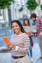 Long-haired girl with orange tablet in her hands on street