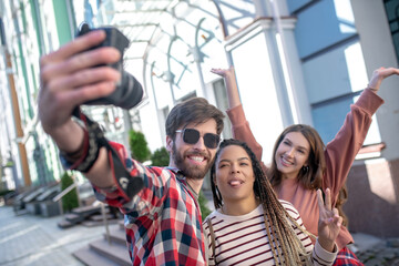 Fototapeta na wymiar Guy taking selfie on camera with two girlfriends.