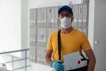 Fototapeta na wymiar Mailman delivering mail with mail-bag and protective mask and gloves during virus pandemic.