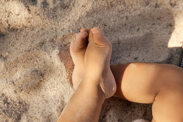 Infant  baby legs on sandy beach as a background at summer time