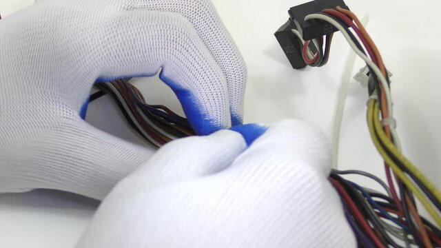 A worker frees a bundle of wires with pliers from a plastic tie.
