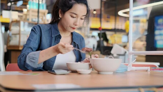 Asian woman sitting separated in restaurant eating food .keep social distance for protect infection from coronavirus covid-19, restaurant and social distancing concept.4k footage.