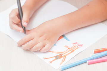 Favorite activity of the child. A happy family. The girl draws with colored markers. Girl's hands.
