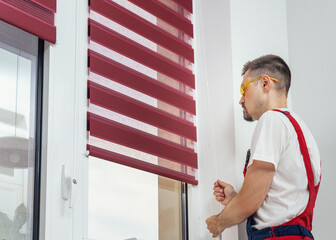 A handyman in a uniform pull rope and closed modern jalousie