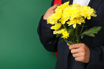 Schoolboy with backpack and chrysanthemums on green background