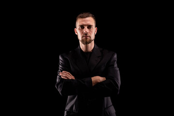 Portrait of a business man in black suit isolated on black background.