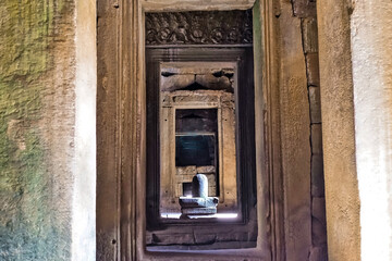 Mysterious Angkor, details. A stone sculpture of the sacred lingam can be seen through the doorway. Light falls on the lingam. The walls are decorated with carvings and ornaments. Cambodia. UNESCO 