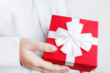 Red box with a bow in female hands. Gift on a white background. Holidays concept birthday, christmas, valentine's day. Copy space