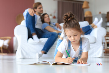 Smiling happy family sit relax on couch in living room watch little daughter drawing in album with colorful pencils. Happy weekends at home.